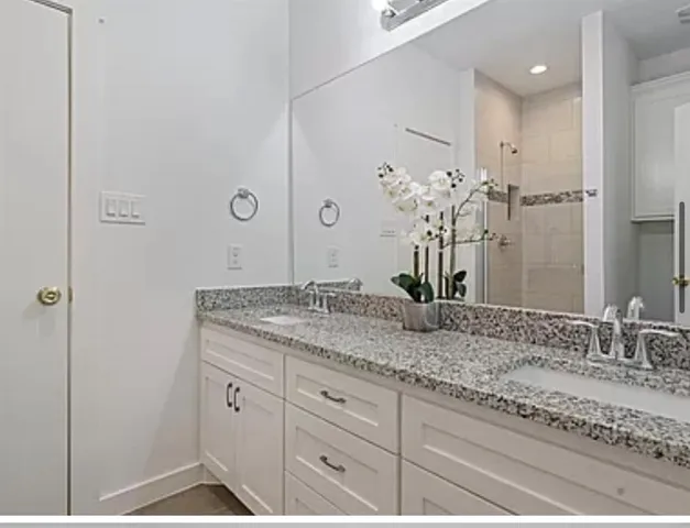 a bathroom with a granite countertop sink a mirror and a shower