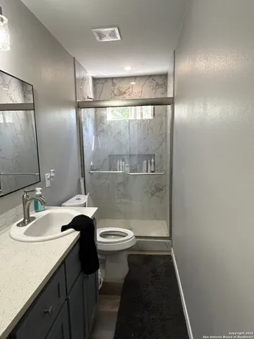 a bathroom with a sink a toilet a mirror and shower