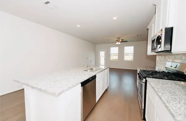 a kitchen with granite countertop a sink stove and cabinets