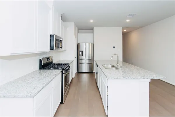 a large kitchen with stainless steel appliances granite countertop a lot of counter space and wooden floor