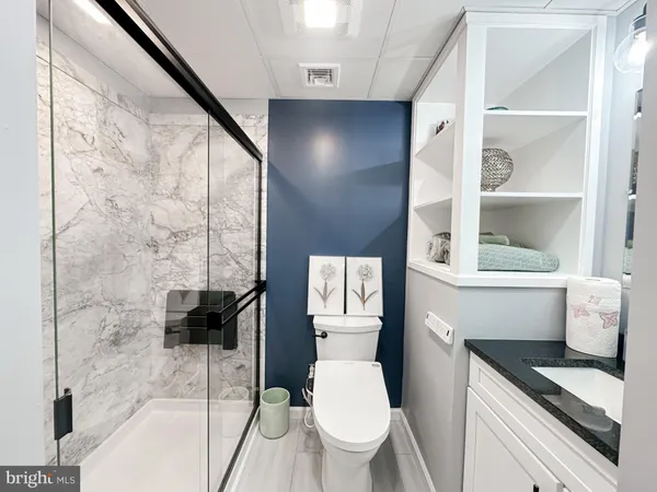 a bathroom with a granite countertop sink a toilet a mirror and shower
