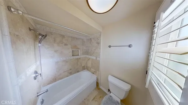 a bathroom with a granite countertop bathtub shower and toilet