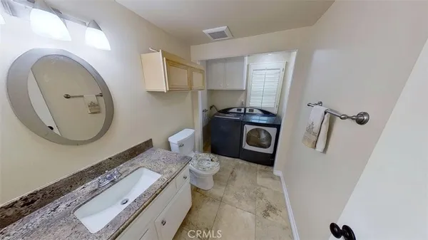 a bathroom with a granite countertop toilet sink and mirror