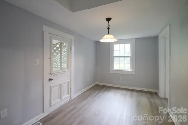a view of an empty room with a window and wooden floor
