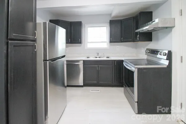 a kitchen with stainless steel appliances granite countertop a refrigerator a sink a stove and a refrigerator