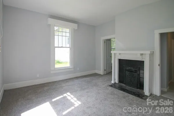 a view of an empty room with window and fire place
