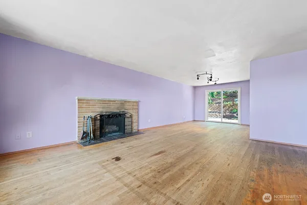 an empty room with windows and fireplace