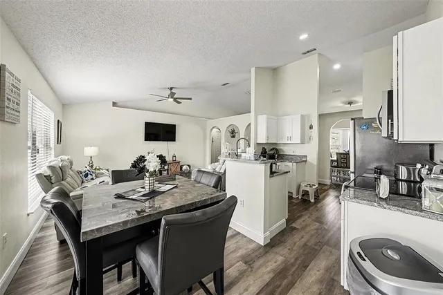 a kitchen with a dining table chairs and refrigerator