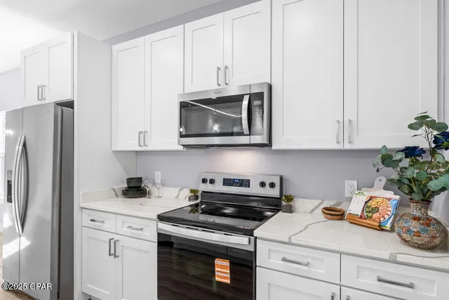 a kitchen with stainless steel appliances white cabinets and a stove a refrigerator with wooden floor