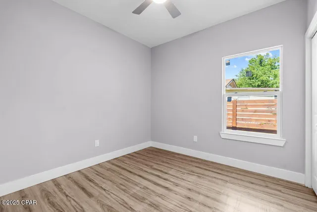 an empty room with a window and a chandelier fan