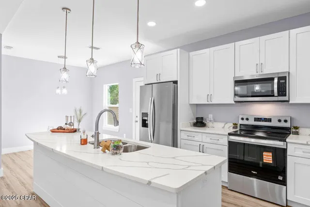 a kitchen with stainless steel appliances granite countertop a sink a stove a refrigerator and cabinets