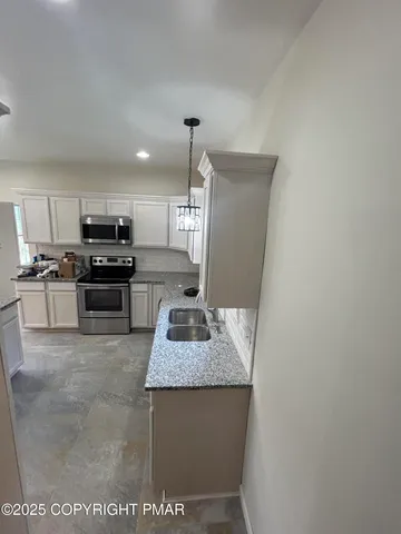 a kitchen with kitchen island granite countertop a sink stove and refrigerator