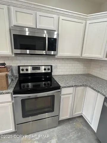 a kitchen with granite countertop a stove and a microwave