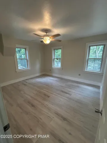 an empty room with windows and fan