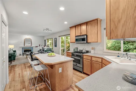 a kitchen with stainless steel appliances granite countertop a sink a stove a refrigerator cabinets and living room view