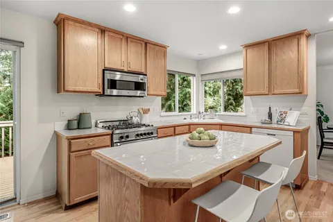 a kitchen with granite countertop kitchen island stainless steel appliances a stove a sink a microwave and cabinets