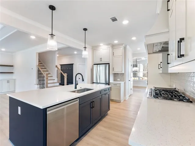 a kitchen with a sink a counter top space stainless steel appliances and cabinets