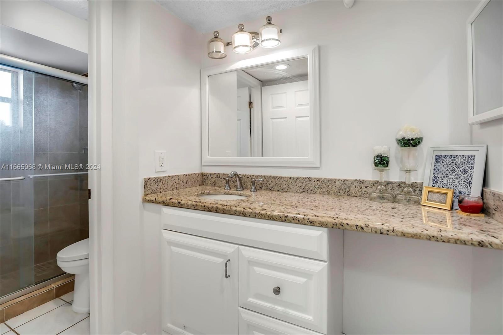 4111 Stirling Road, Unit 304 Fort Lauderdale, FL 33314 - Photo 13 of 22 a bathroom with a granite countertop sink a toilet and a mirror