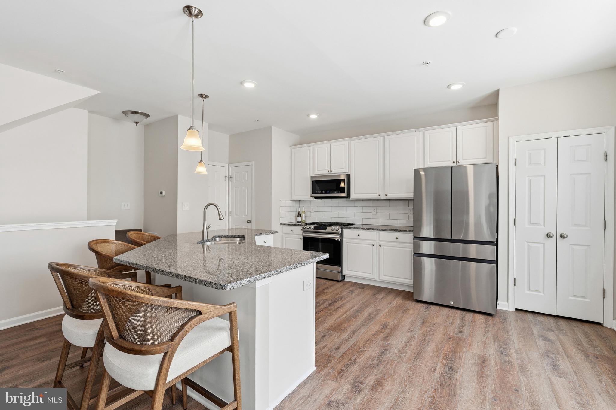 5902 Forum Square Frederick, MD 21703 - Photo 7 of 28 a kitchen with stainless steel appliances granite countertop a refrigerator a sink a stove a dining table and chairs