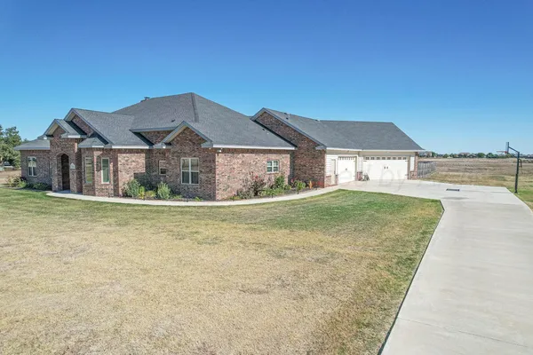 a front view of a house with a yard and mountain view in back