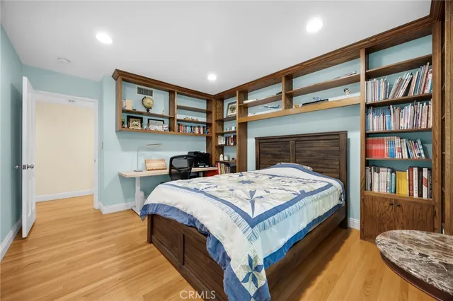 a spacious bedroom with a bed a dresser and a book shelf