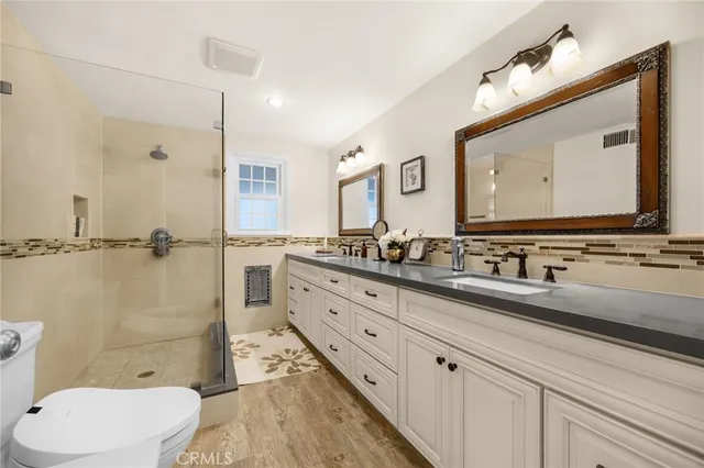 a bathroom with a toilet a sink a mirror and a shower