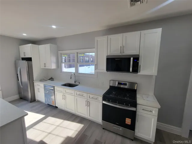 a kitchen with stainless steel appliances granite countertop a stove a sink a refrigerator and a microwave