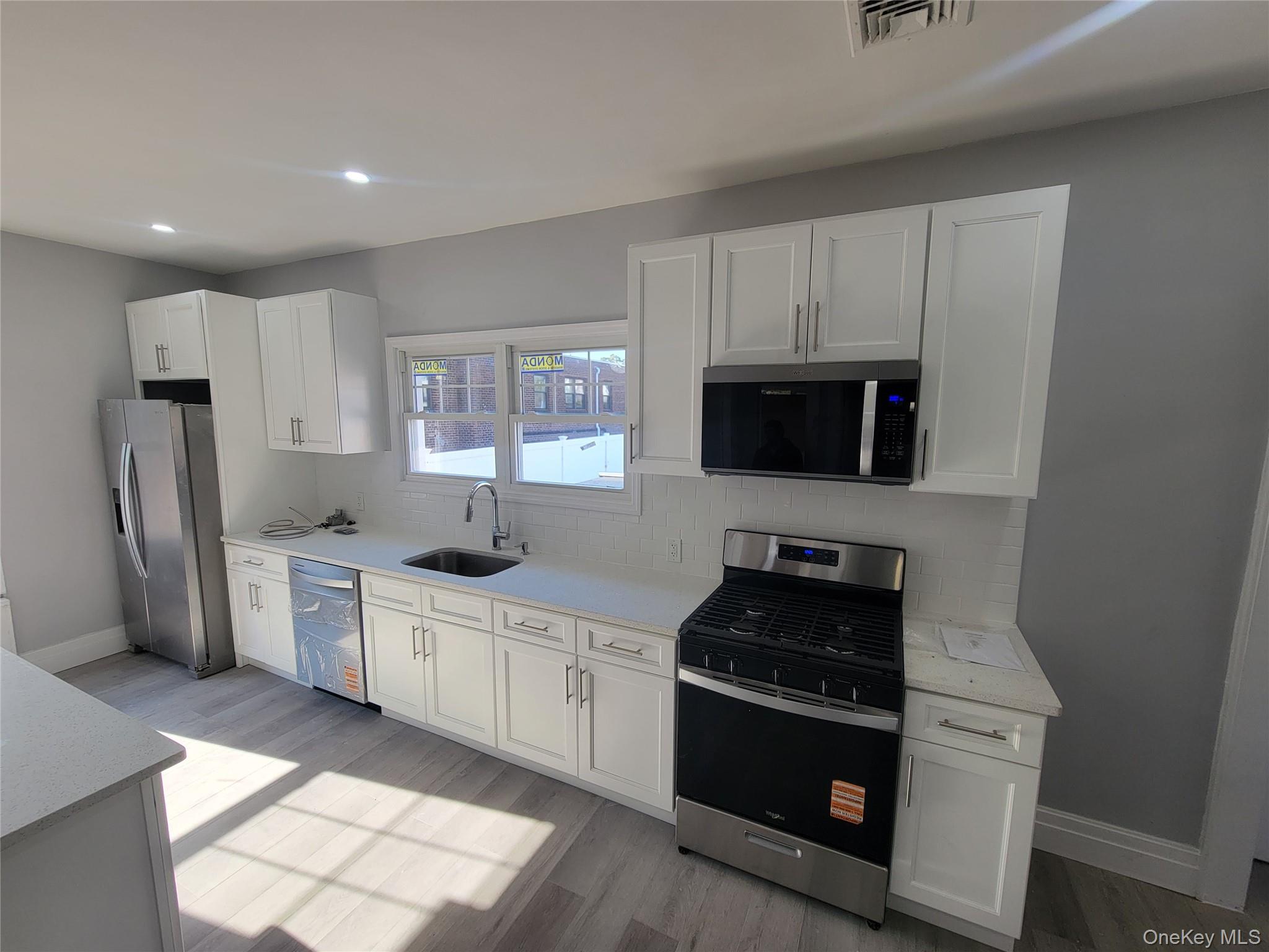 315 Mill Road Hewlett, NY 11557 - Photo 11 of 12 a kitchen with white cabinets and stainless steel appliances