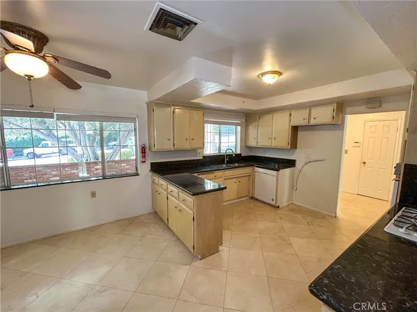 a large kitchen with granite countertop a stove top oven a sink a counter space and cabinets