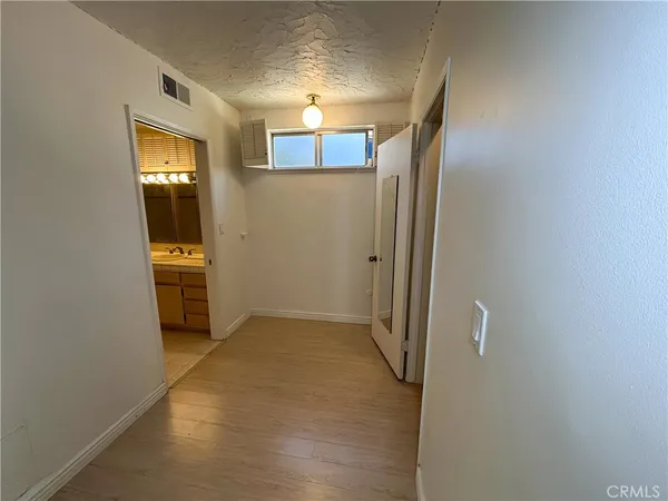 a view of a hallway with wooden floor and a cabinet