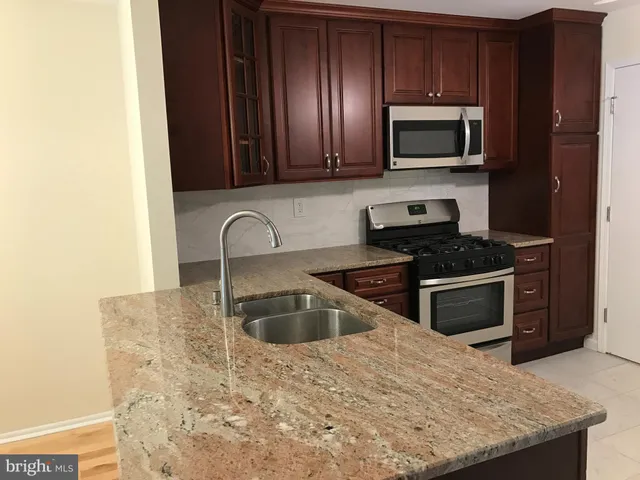 a kitchen with granite countertop a sink and a stove top oven with wooden floor