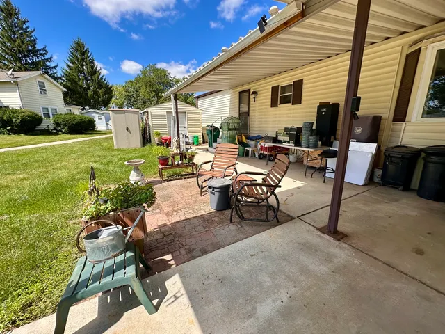 a view of a patio with table and chairs potted plants and a large tree