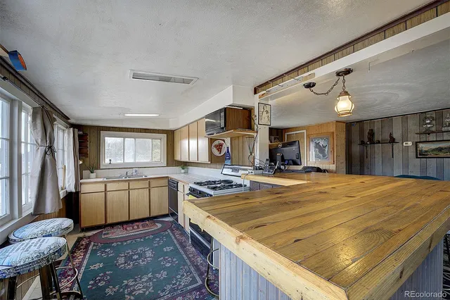a kitchen with stainless steel appliances granite countertop sink stove refrigerator dining table and chairs