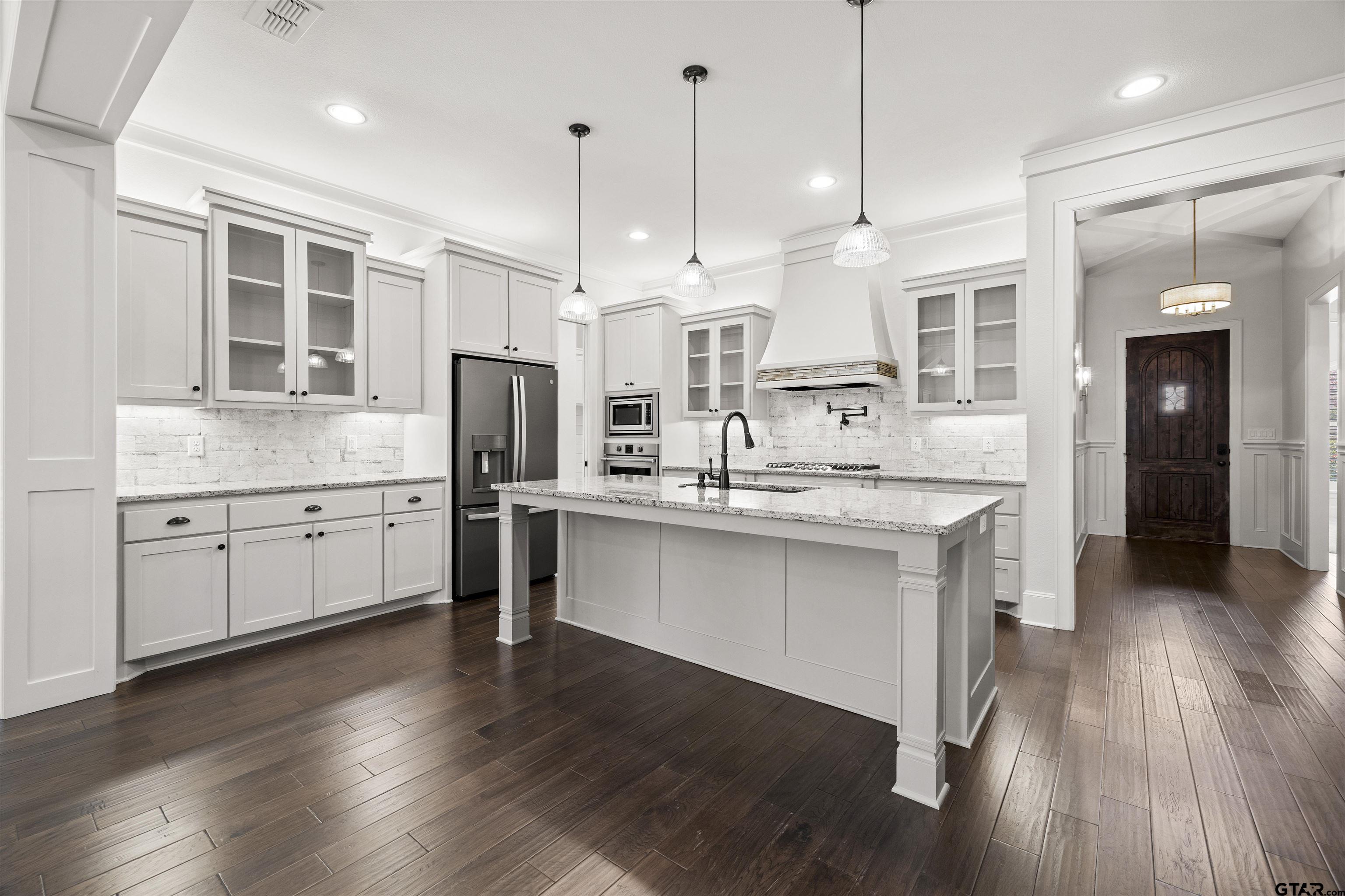7384 Lake Pointe Cove Tyler, TX 75703 - Photo 5 of 18 a large white kitchen with a refrigerator a sink dishwasher a oven and a dining table with wooden floor