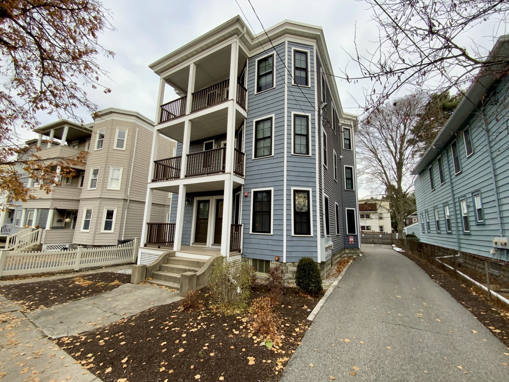 65 Broadway, Unit 1 Arlington, MA 02474 - Photo 15 of 15 a front view of a residential apartment building with a yard