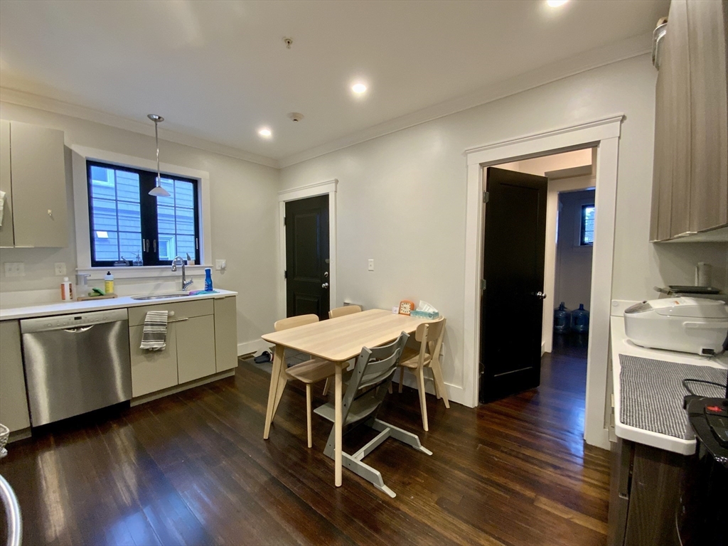 65 Broadway, Unit 1 Arlington, MA 02474 - Photo 8 of 15 a kitchen with a table chairs sink and cabinets