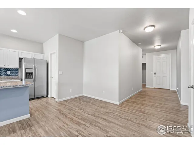 a view of an empty room with kitchen and window