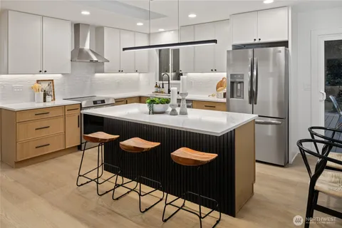 a kitchen with stainless steel appliances granite countertop a refrigerator a sink a stove a dining table and chairs