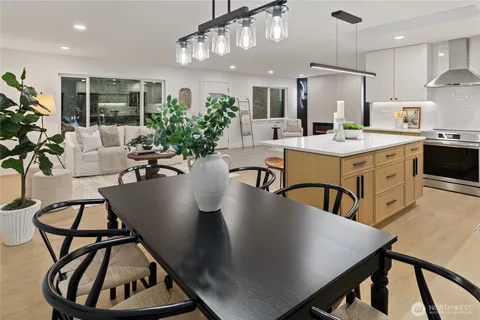 a living room with stainless steel appliances kitchen island a table chairs stove and sink