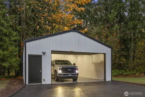 a view of backyard of house and car parked on road