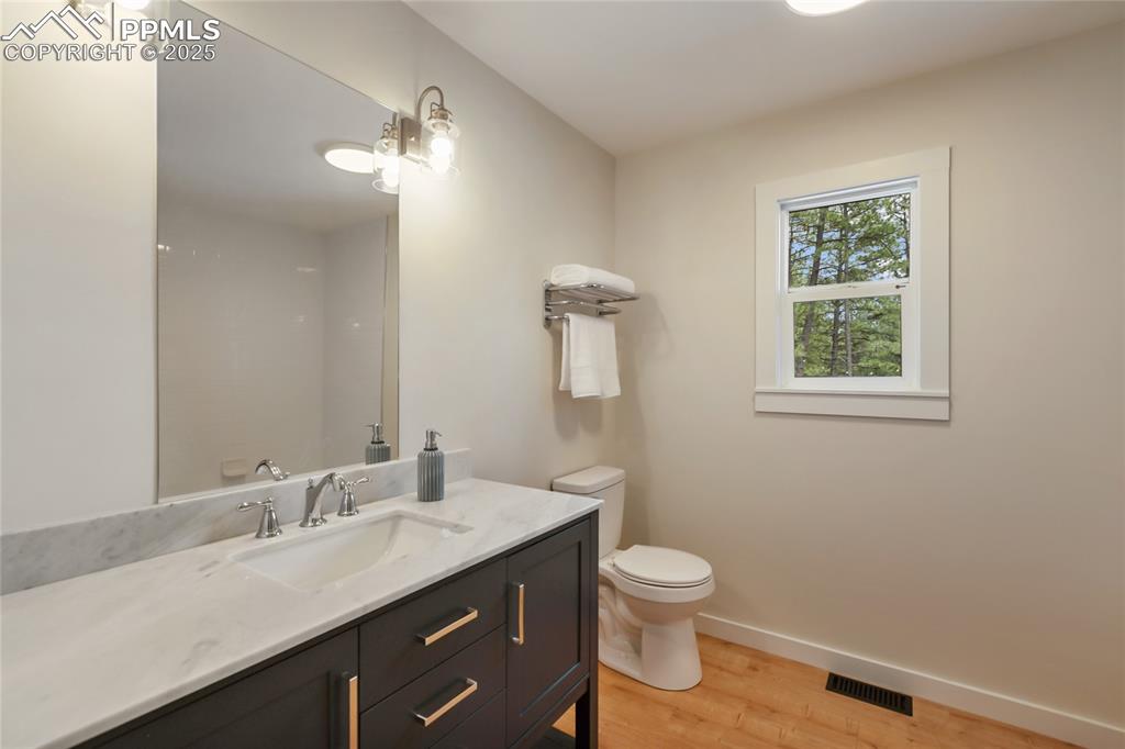 1320 Spring Valley Drive Colorado Springs, CO 80921 - Photo 27 of 46 a bathroom with a granite countertop toilet a sink and a mirror