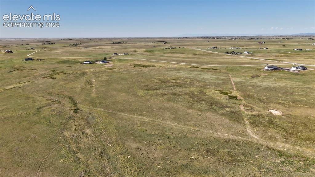 8007 Wrangler Ranch View Peyton, CO 80831 - Photo 6 of 9 Expansive open land featuring natural grasses and distant residential structures under a clear sky