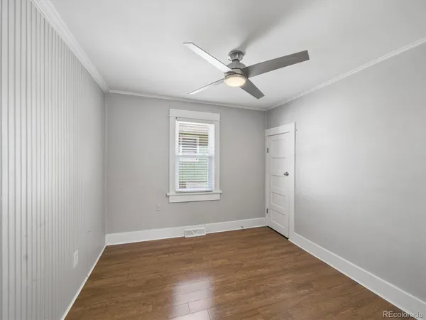 an empty room with wooden floor fan and windows