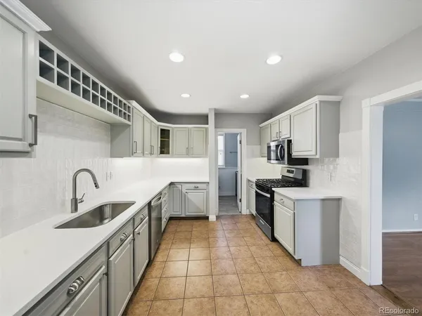 a large white kitchen with stainless steel appliances granite countertop a sink and dishwasher a stove top oven with wooden floor