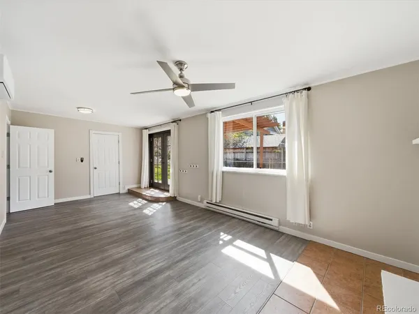 a view of an empty room with wooden floor and a window