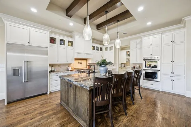 a kitchen with stainless steel appliances kitchen island granite countertop a table chairs and a refrigerator