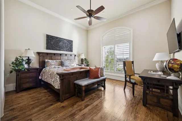 a bedroom with a bed a desk and chair with wooden floor