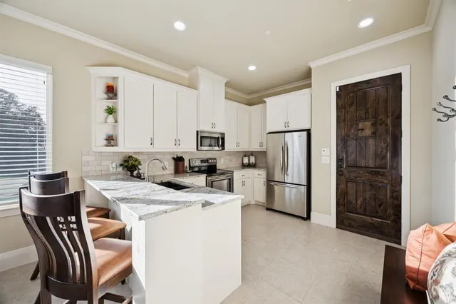 a kitchen with a dining table chairs refrigerator and microwave