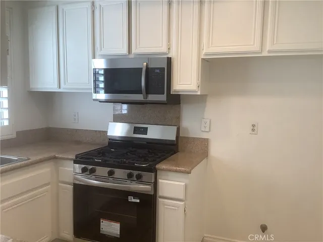 a kitchen with stainless steel appliances granite countertop white cabinets and a stove top oven
