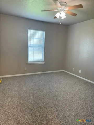 an empty room with a chandelier fan and windows